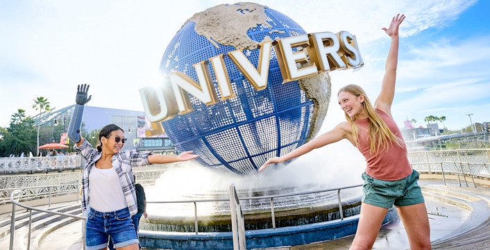 Guests posing in front of the Universal globe with a water fountain at the Universal Studios resort in Orlando, Florida