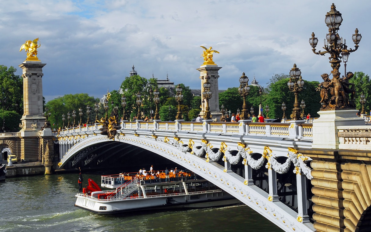 Seine River cruise boat passing under Pont Alexandre III in Paris.