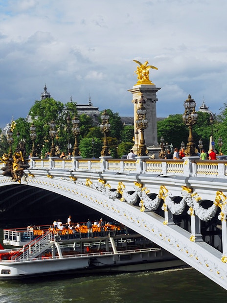 Seine River cruise boat passing under Pont Alexandre III in Paris.