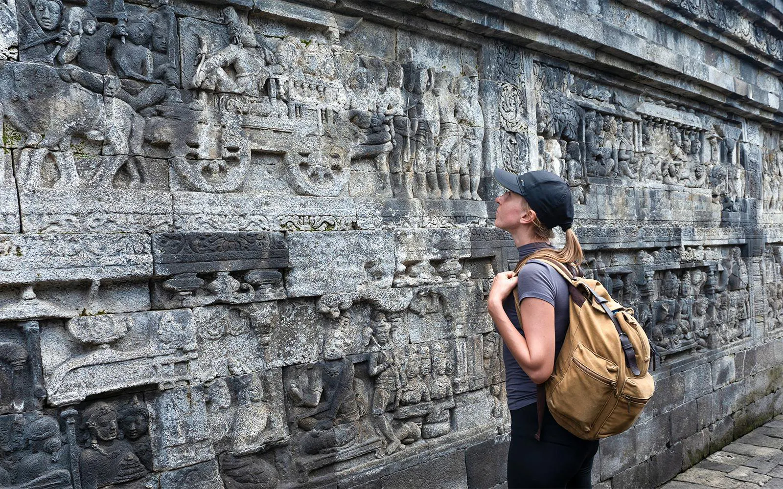 Backpacker admiring stone carvings at Borobudur Temple, Java, Indonesia.