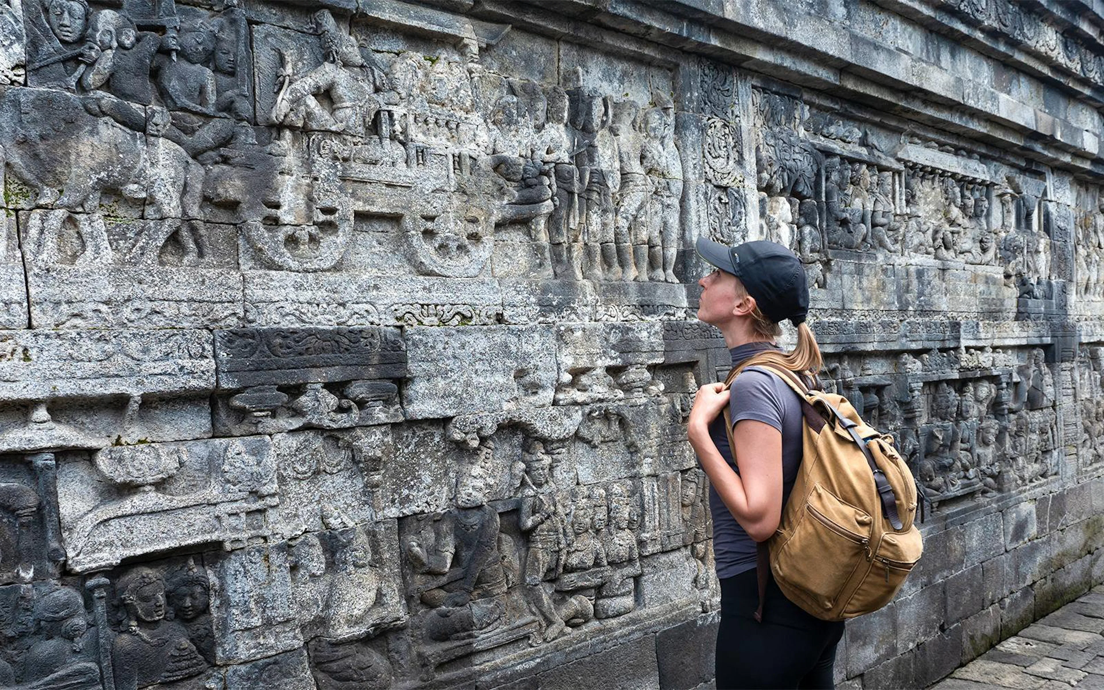 Backpacker admiring stone carvings at Borobudur Temple, Java, Indonesia.