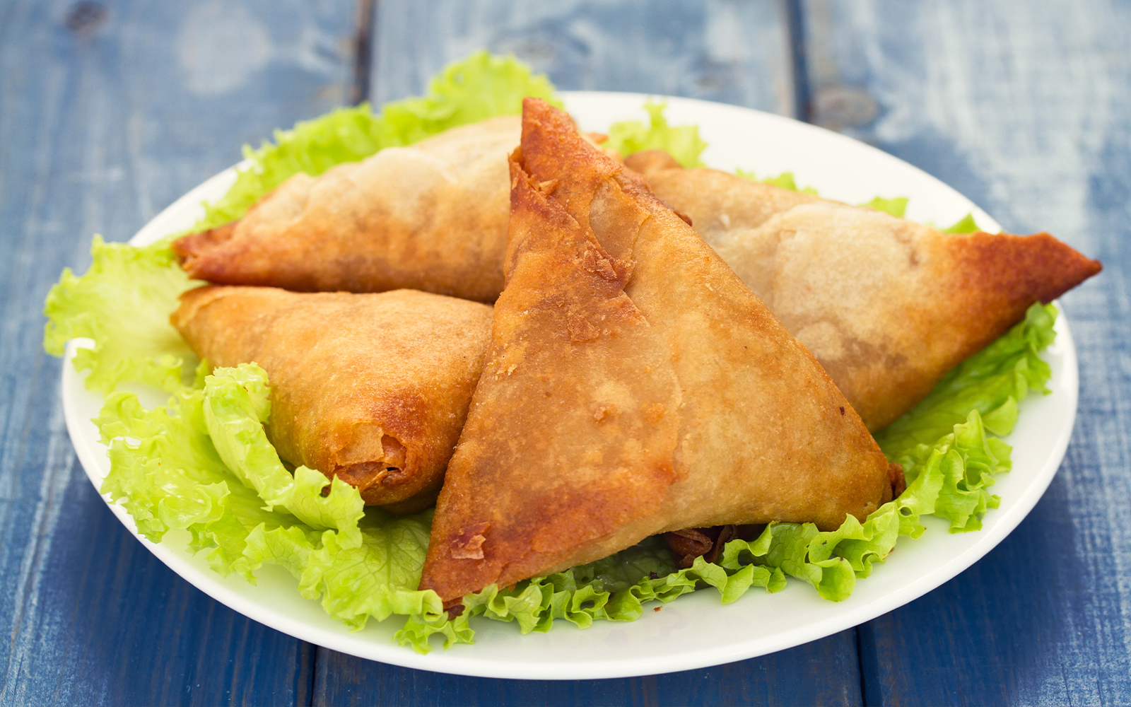 Mozambican samosas on a plate with lettuce, showcasing Portuguese culinary influence.