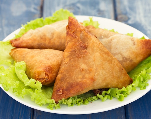 Mozambican samosas on a plate with lettuce, showcasing Portuguese culinary influence.