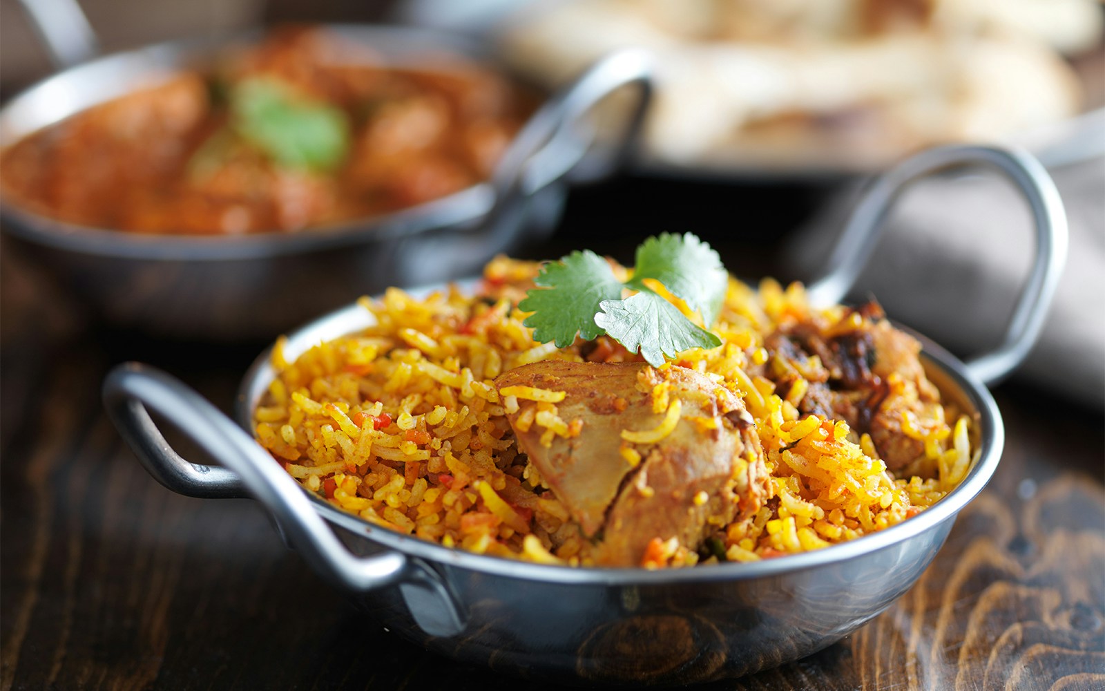 Chicken biryani served in a traditional Indian bowl with cilantro garnish.