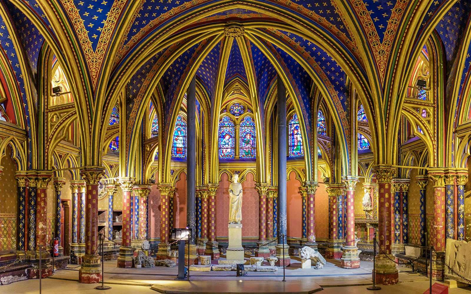 Visiteurs explorant les vitraux complexes de la chapelle inférieure de la Sainte Chapelle lors d'une visite guidée à Paris.