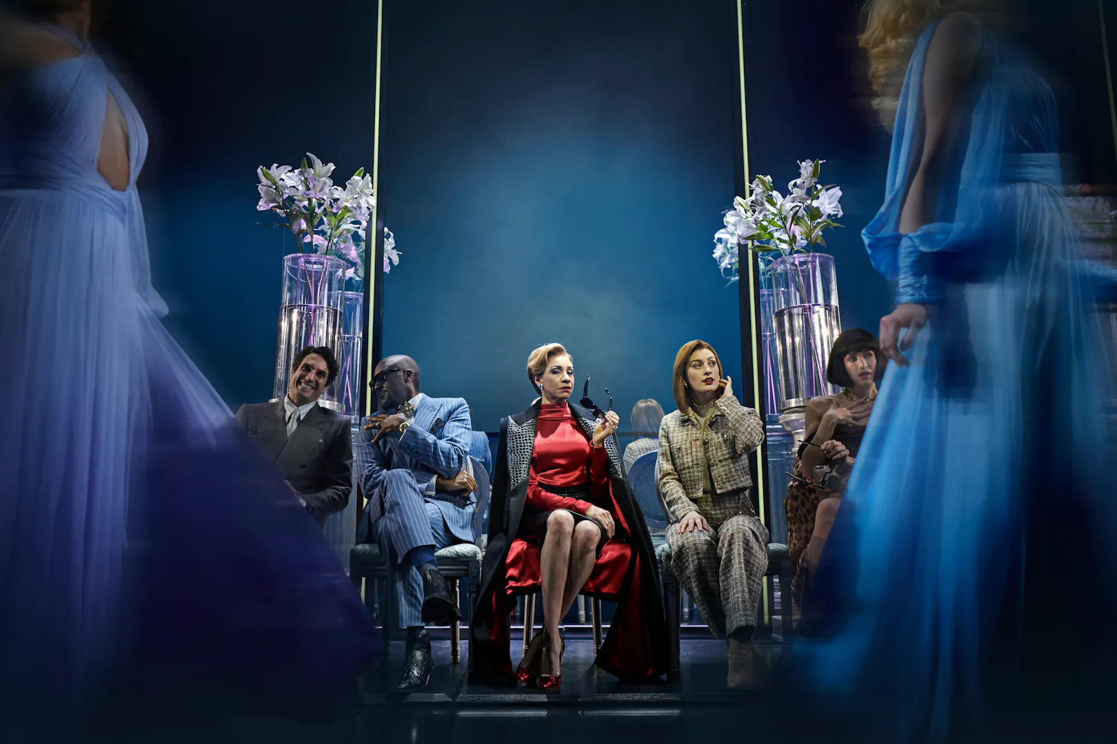 Performance scene from The Devil Wears Prada in Hamburg, featuring seated characters and elegant costumes.