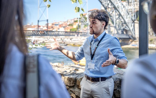 Tour guide explaining by the Dom Luís I Bridge in Porto during a city tour.