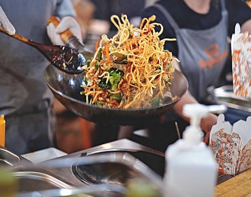 Stir-fried noodles being prepared at a street food stall during Bangkok Night Bike Tour.