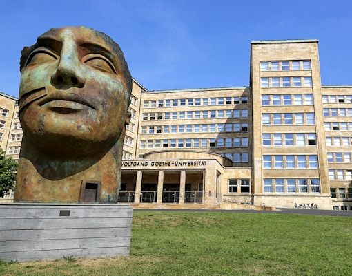 Goethe University Frankfurt entrance with large bronze sculpture in foreground.
