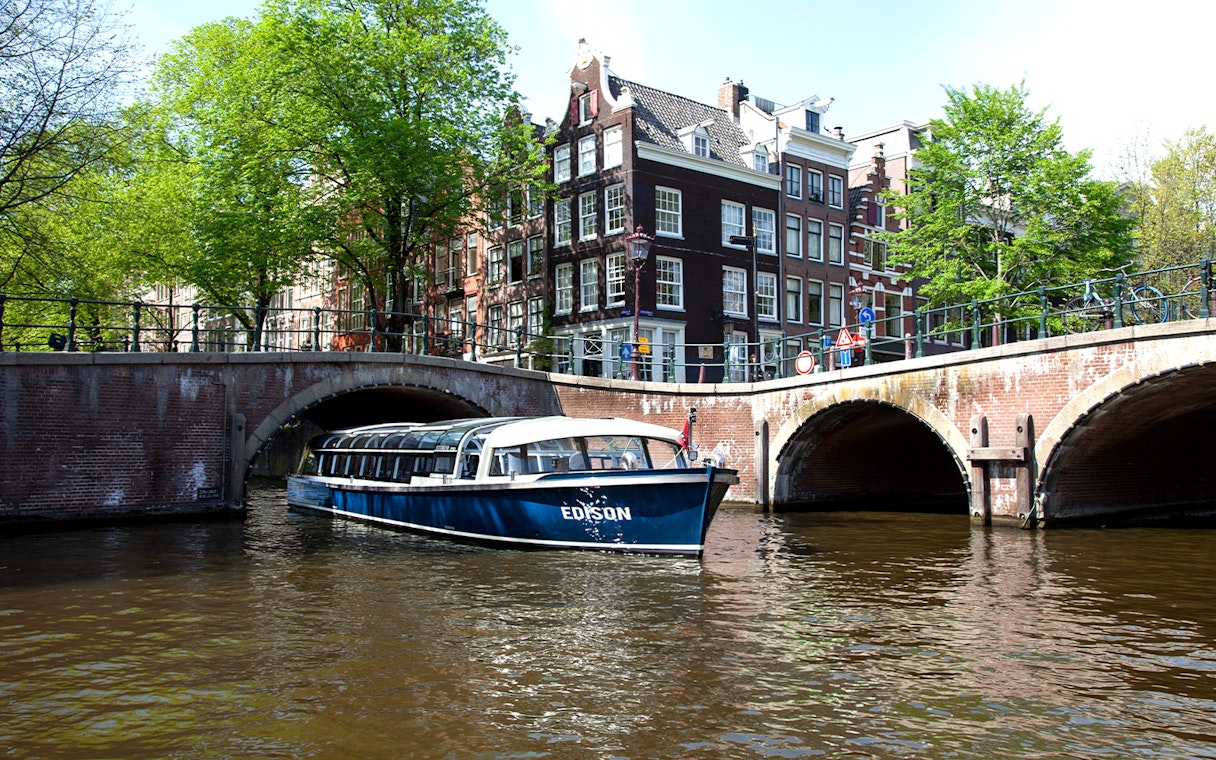 Canal boat under bridge in Amsterdam near STRAAT Museum.