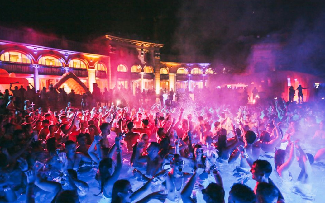 Crowd enjoying a vibrant bath party at night in Budapest.