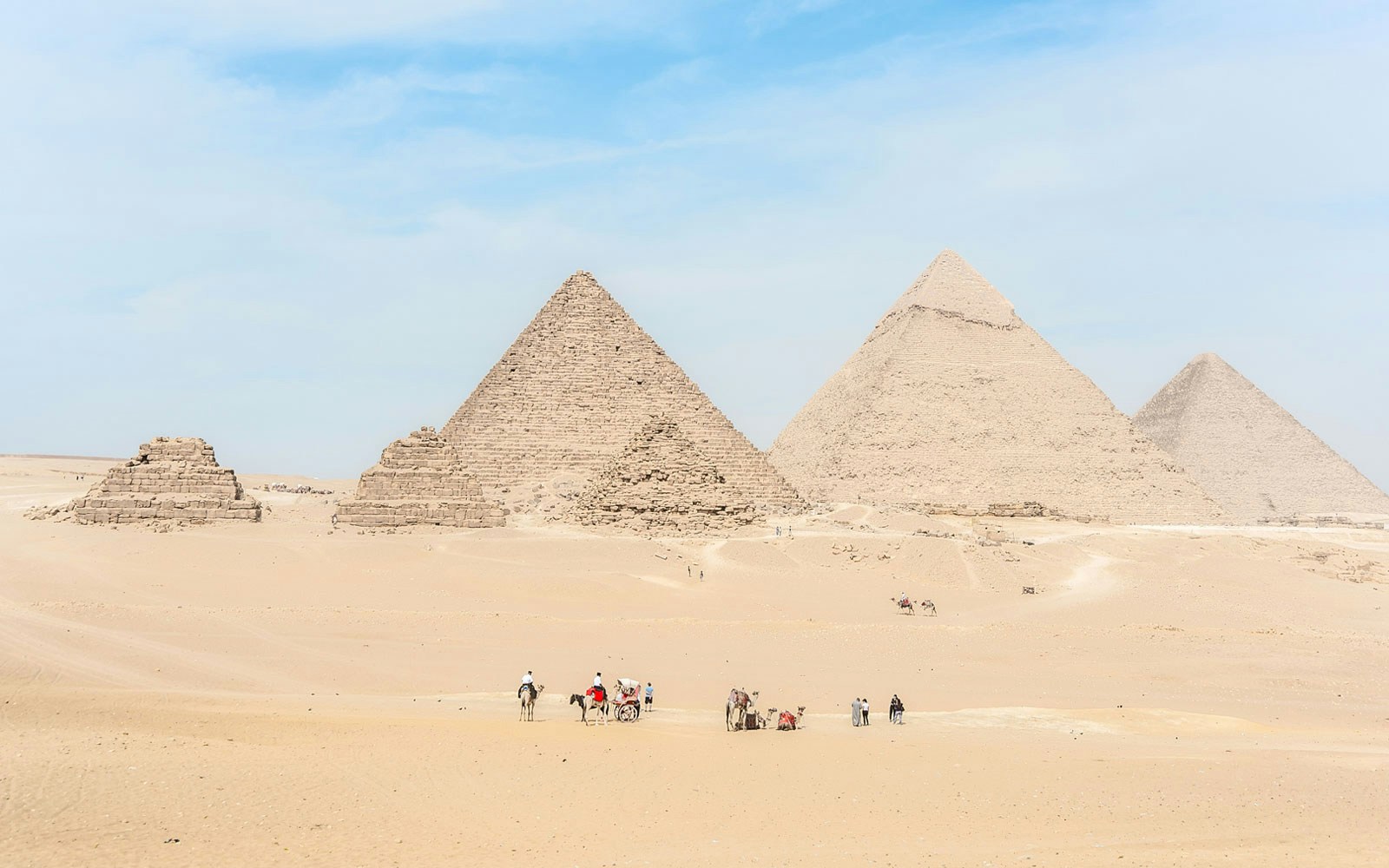 Giza Pyramids with tourists and camels in the desert near Cairo, Egypt.