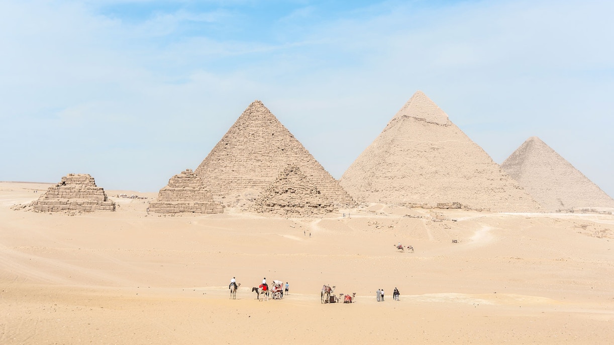 Giza Pyramids with tourists and camels in the desert near Cairo, Egypt.
