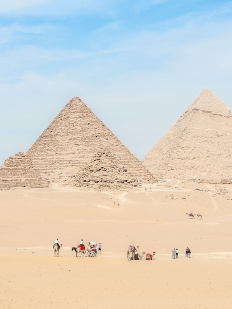 Giza Pyramids with tourists and camels in the desert near Cairo, Egypt.