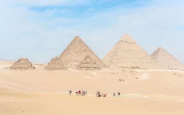 Giza Pyramids with tourists and camels in the desert near Cairo, Egypt.