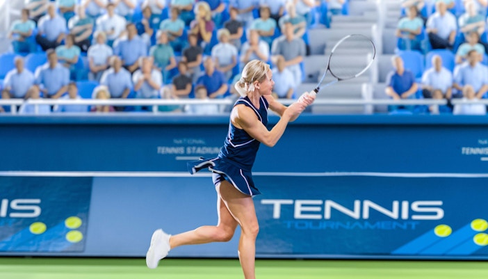 Tennis player hitting a backhand shot at the US Open tournament.