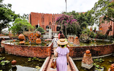 Visitors exploring a traditional craft village with brick architecture and gardens in Hoi An.