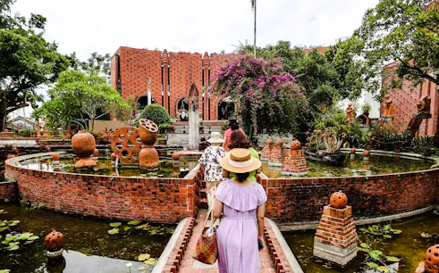 Visitors exploring a traditional craft village with brick architecture and gardens in Hoi An.