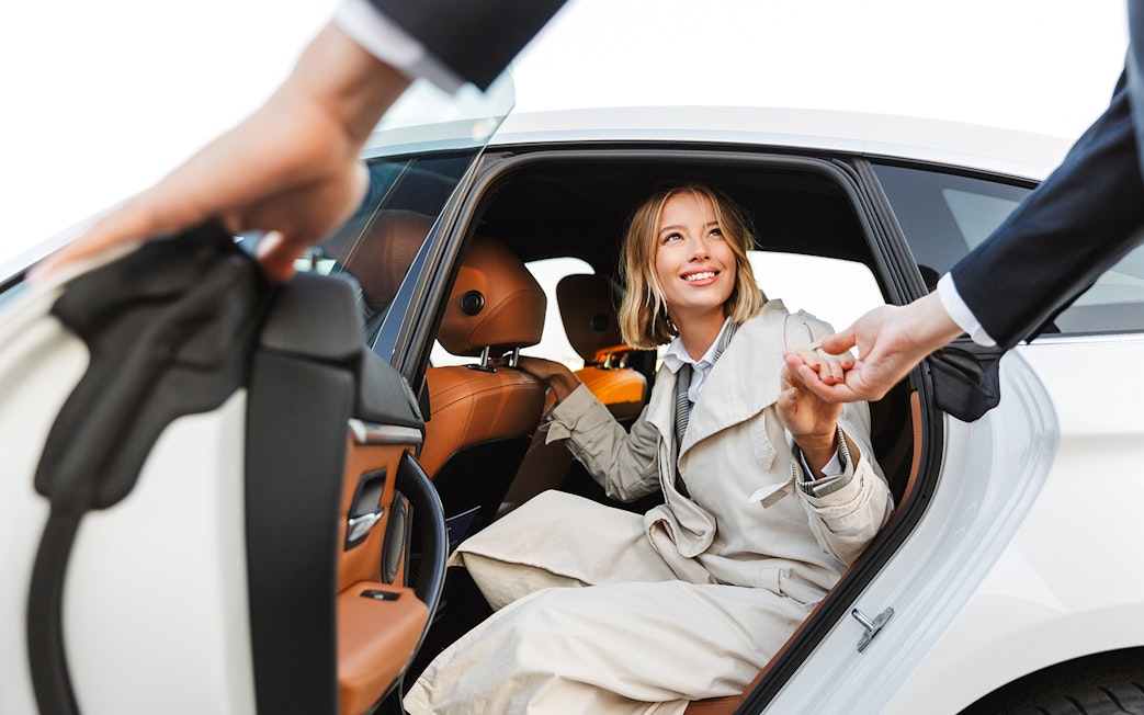 Woman exiting a car with assistance, smiling, during a tour transfer.