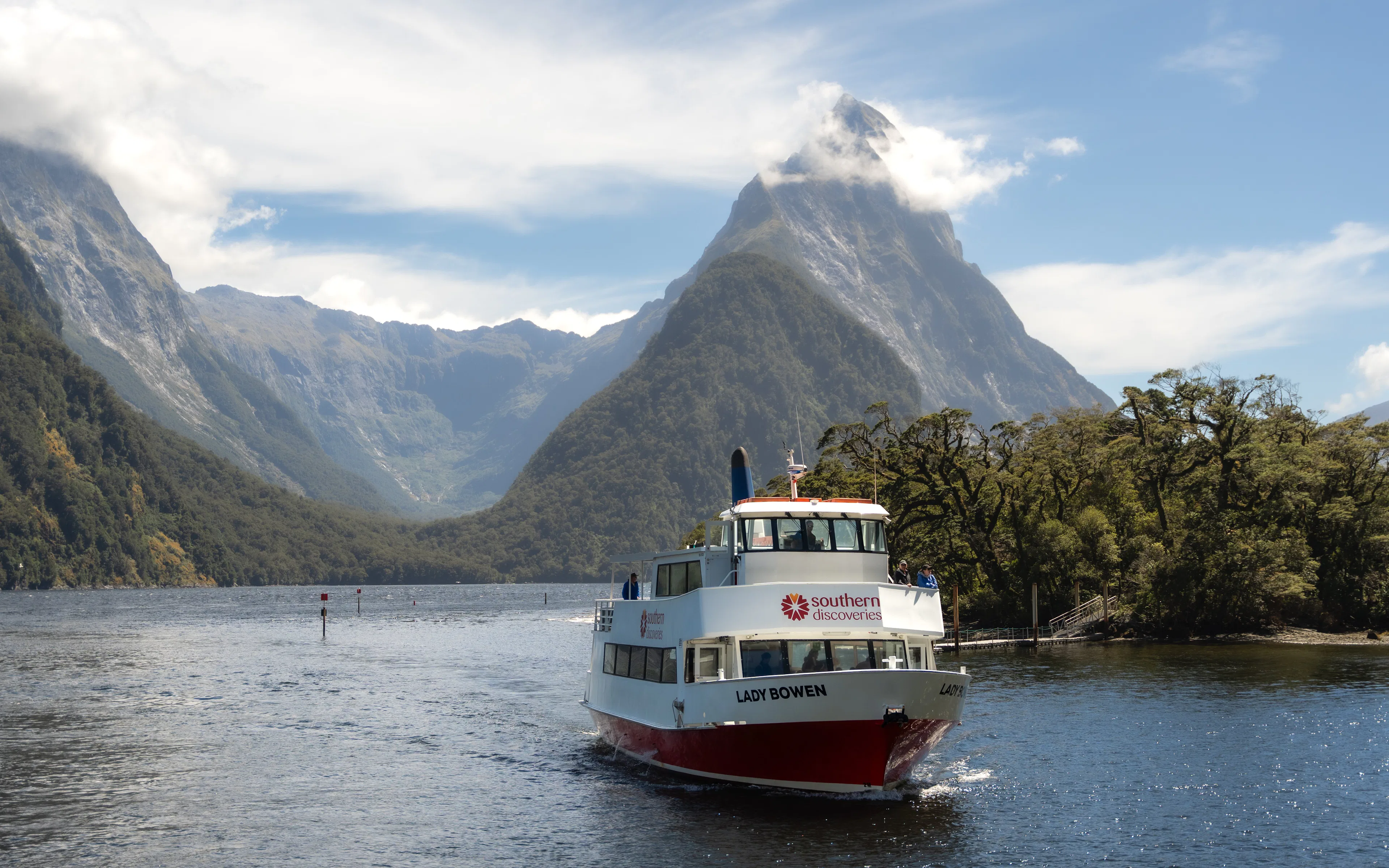 Cruise boat on Milford Sound with Mitre Peak in the background, New Zealand.