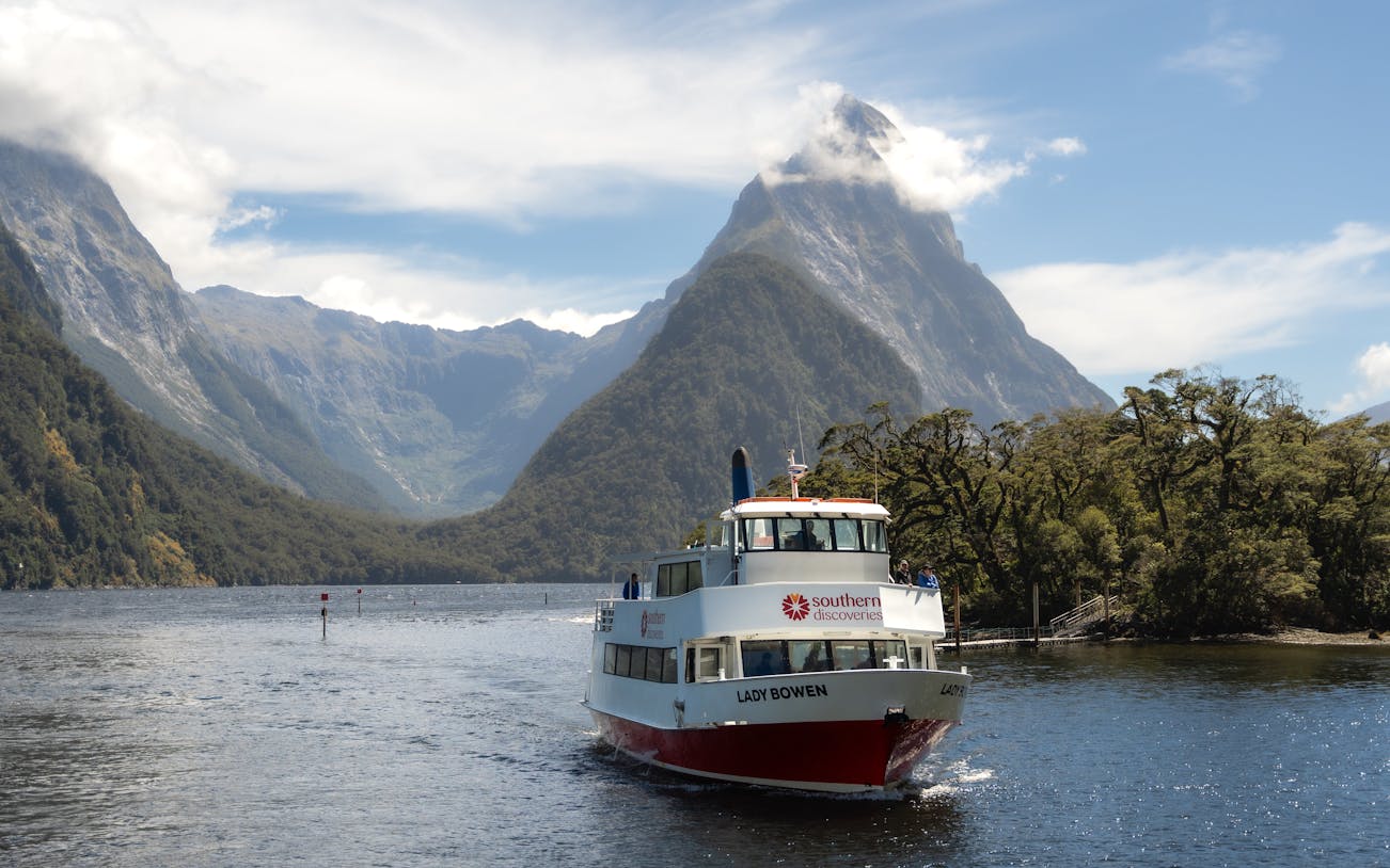 Cruise boat on Milford Sound with Mitre Peak in the background, New Zealand.