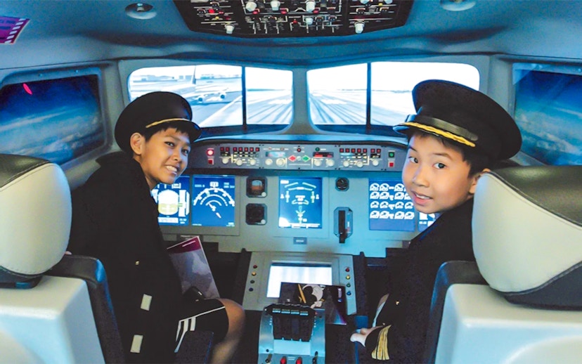 Kids in pilot uniforms in airplane cockpit simulator at KidZania.