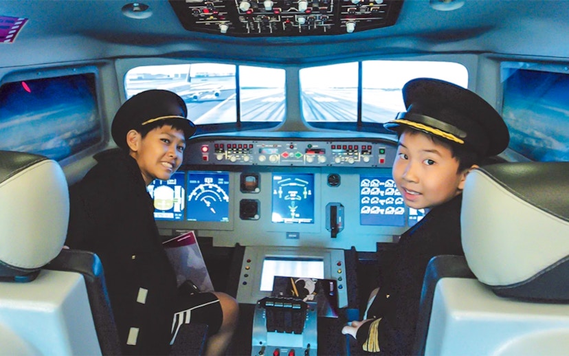 Kids in pilot uniforms in airplane cockpit simulator at KidZania.