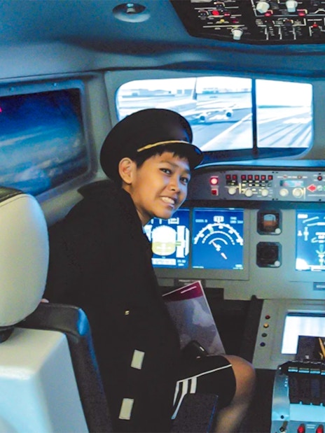 Kids in pilot uniforms in airplane cockpit simulator at KidZania.