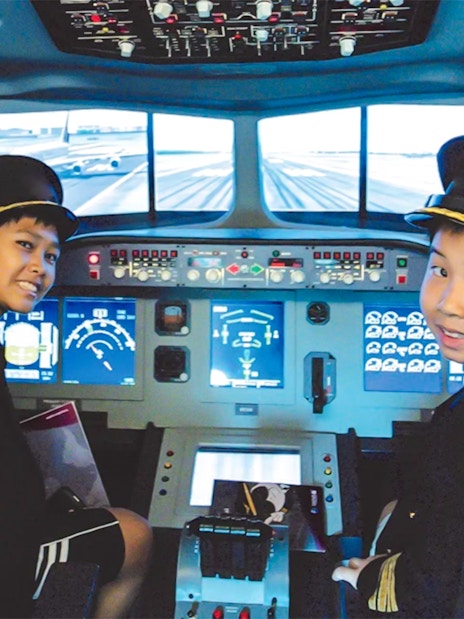 Kids in pilot uniforms in airplane cockpit simulator at KidZania.