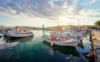 Boats docked at Aegina harbor during sunset, starting point for Agistri and Metopi Islands cruise.