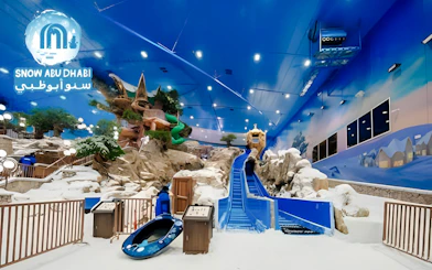 Indoor snow park with slides and snow-covered landscape, Snow Abu Dhabi, UAE.
