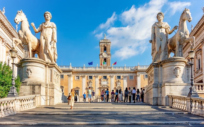 Visitors at Capitoline Museums entrance in Rome, flanked by statues of Castor and Pollux.