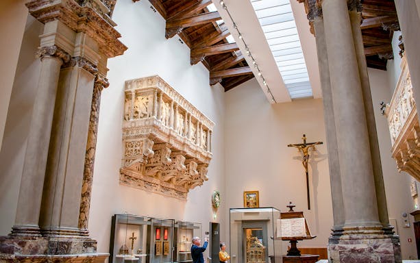 Florence Duomo Museum interior with sculptures and visitors exploring exhibits.