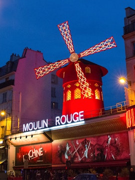 Moulin Rouge cabaret show in Paris with iconic red windmill and vibrant lights.