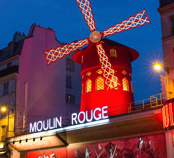 Moulin Rouge cabaret show in Paris with iconic red windmill and vibrant lights.