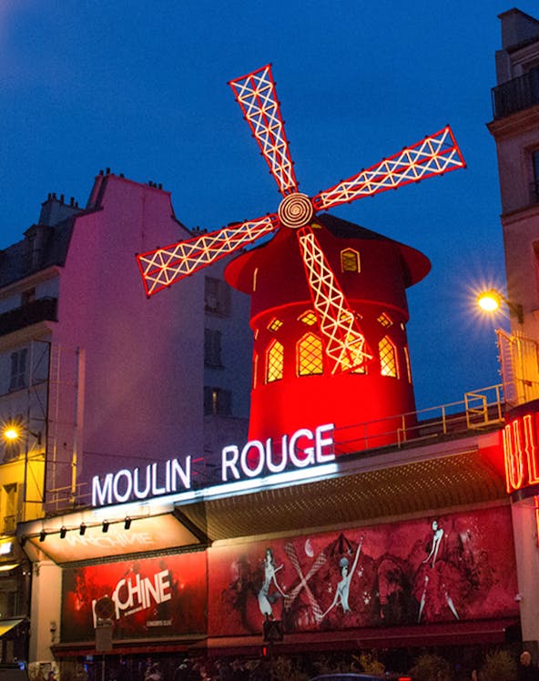 Moulin Rouge cabaret show in Paris with iconic red windmill and vibrant lights.