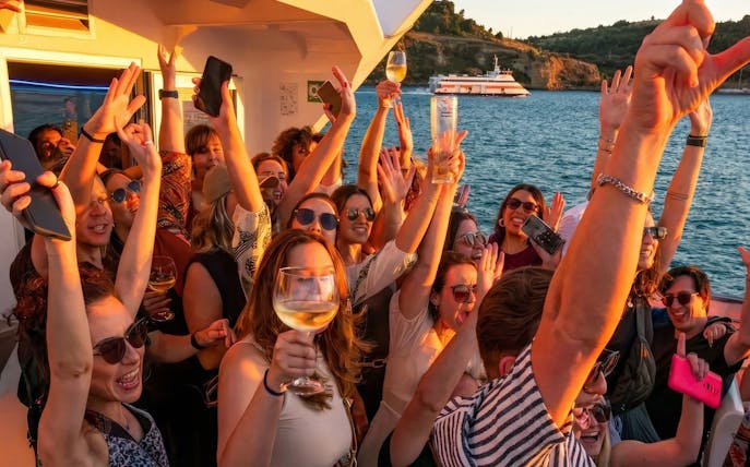 Guests dancing and enjoying a DJ performance on a Lisbon sunset party cruise with open bar.