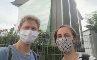 Visitors wearing masks in front of a modern building in Singapore during a self-guided city exploration game.