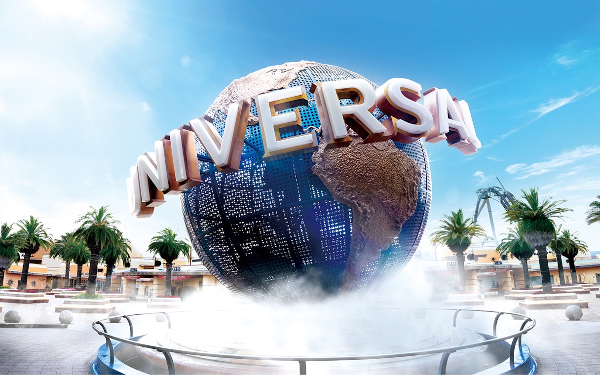 Universal Studios Japan globe with palm trees and clear sky.