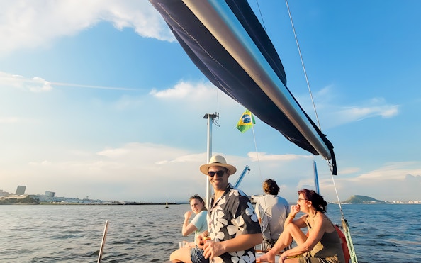 Tourists on sailboat enjoying Rio de Janeiro view at sunset.