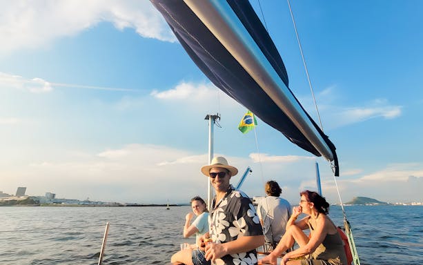 Tourists on sailboat enjoying Rio de Janeiro view at sunset.