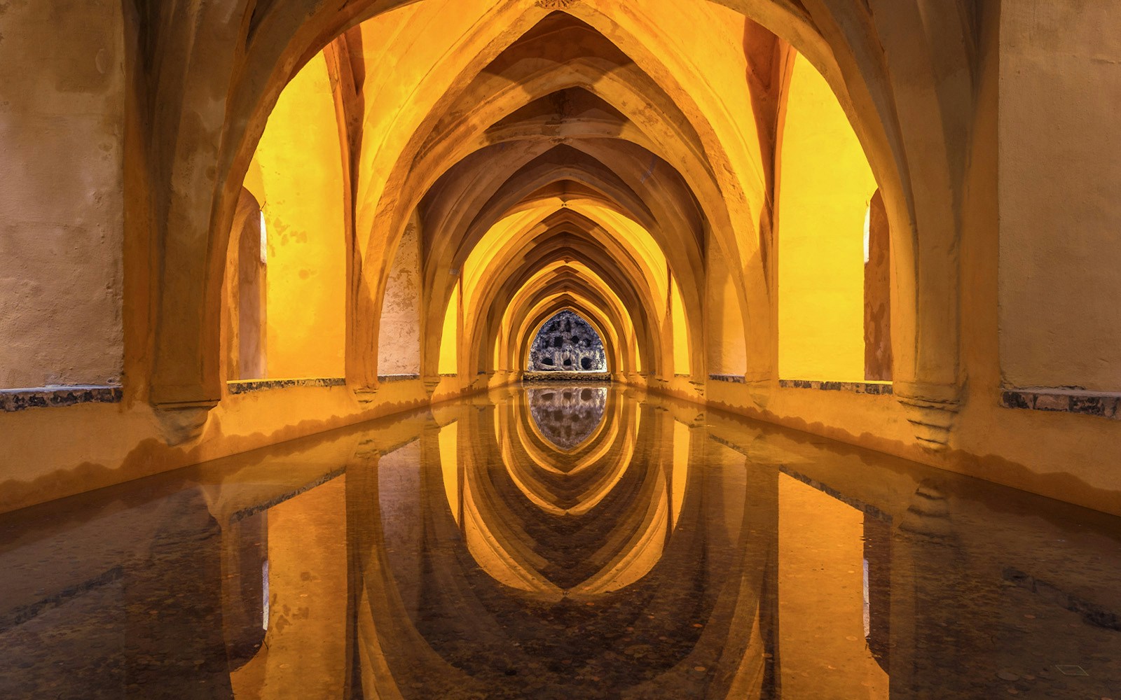 Tourists exploring the stunning architecture of Alcazar of Seville, with a glimpse of Seville Cathedral and Giralda in the background, available with skip-the-line tickets