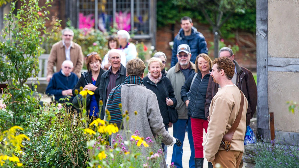 Tour group in Stratford garden during Stratford, Oxford, Cotswolds & Warwick Castle tour.