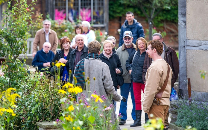 Tour group in Stratford garden during Stratford, Oxford, Cotswolds & Warwick Castle tour.