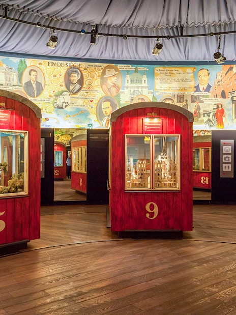 Red exhibition pods at The Wheel of History ‘Panorama’ with historical murals in the background.