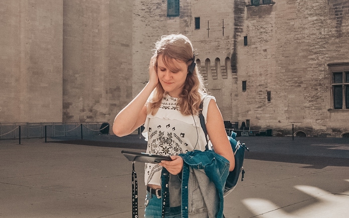 Visitor using audio guide at Carcassonne Castle courtyard.