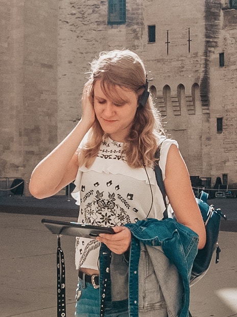Visitor using audio guide at Carcassonne Castle courtyard.