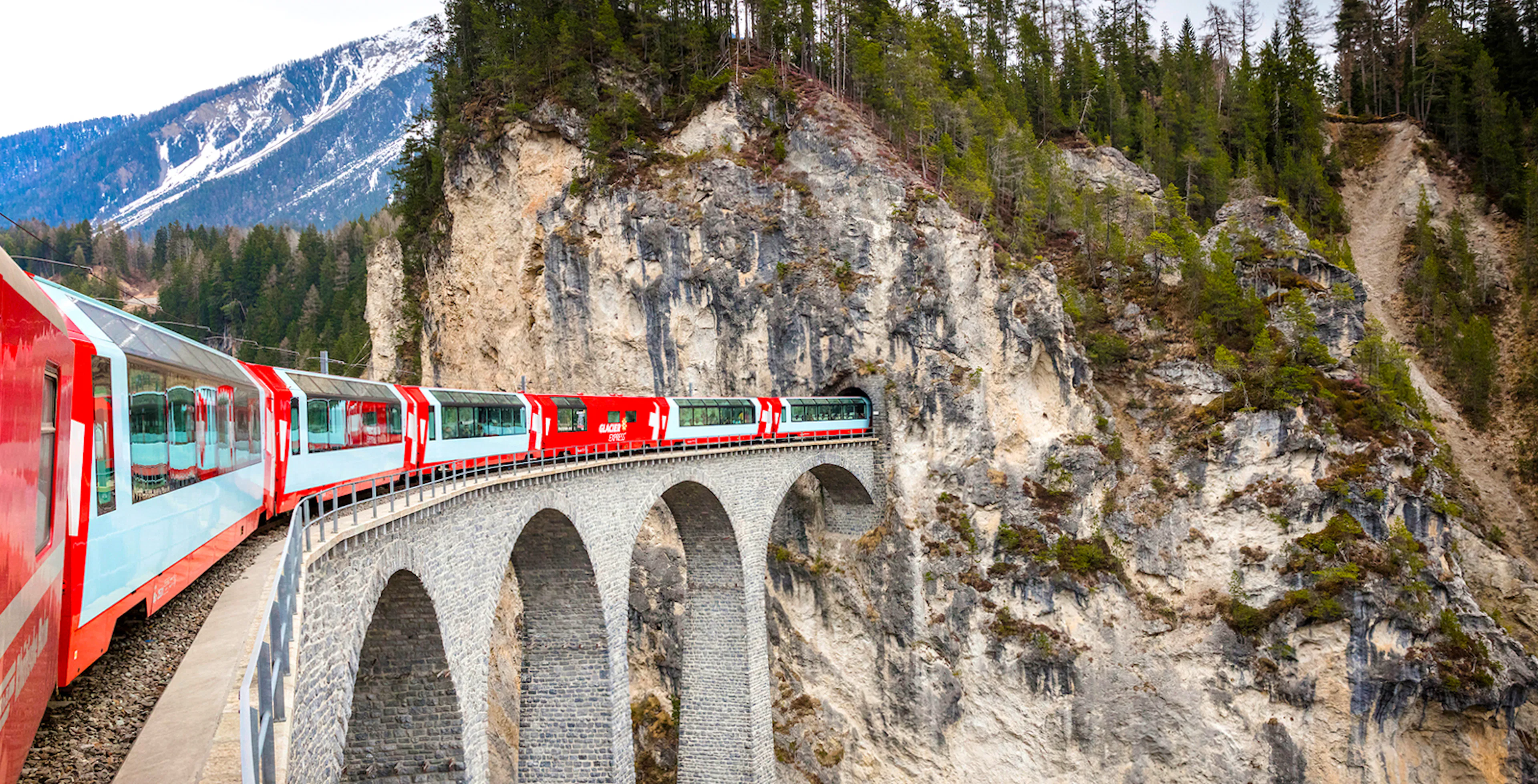 Glacier Express train crossing a stone viaduct in the Swiss Alps.