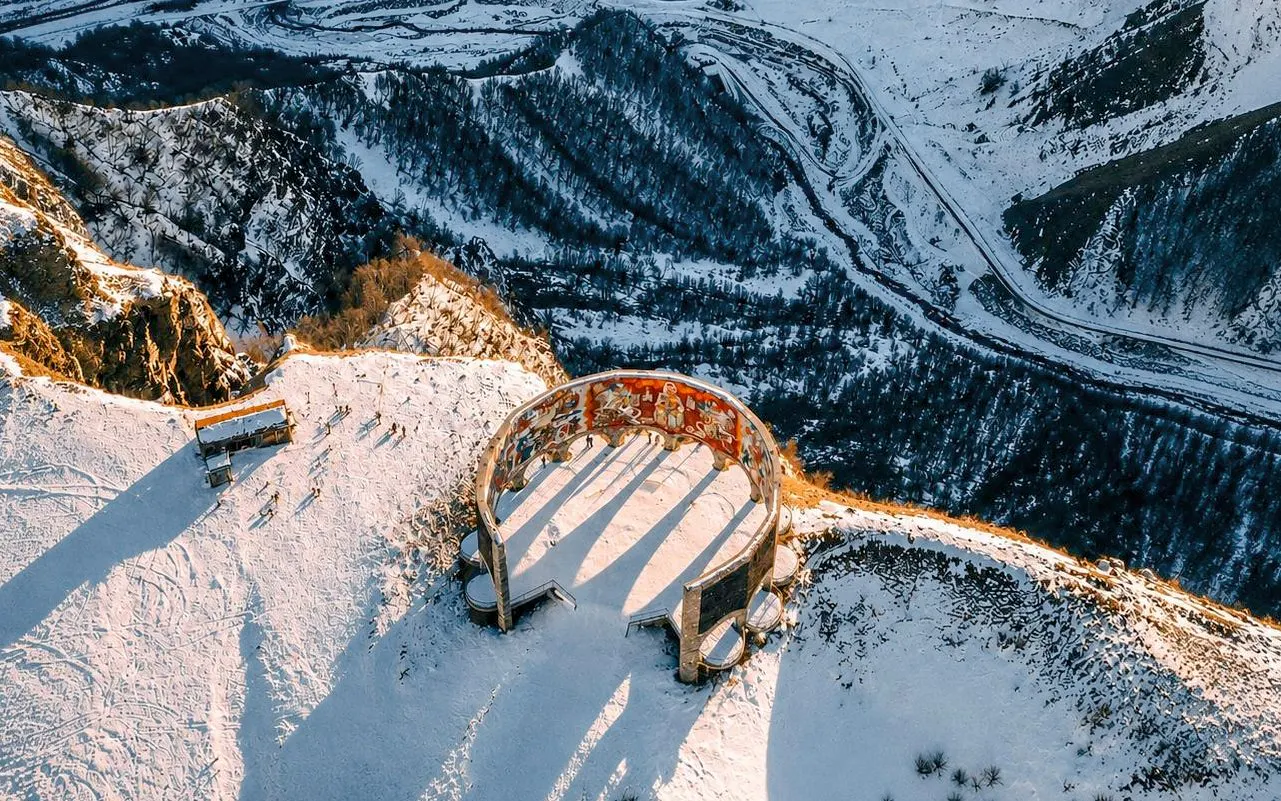 Gudauri View Point in snowy Caucasus Mountains, Georgia, with circular monument.