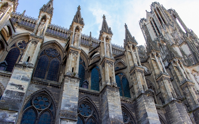 Notre-Dame de Reims, France, showcasing Gothic flying buttresses and detailed stone carvings.